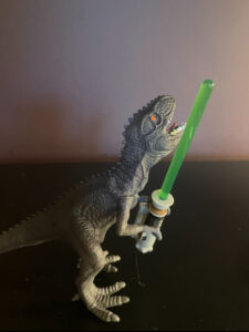 Toy dinosaur holding a light saber